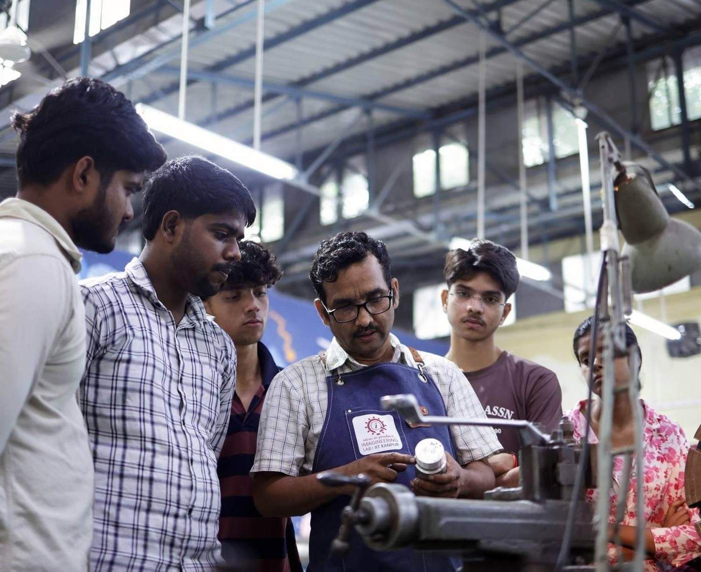 Students learning on a machine in a workshop with a faculty member