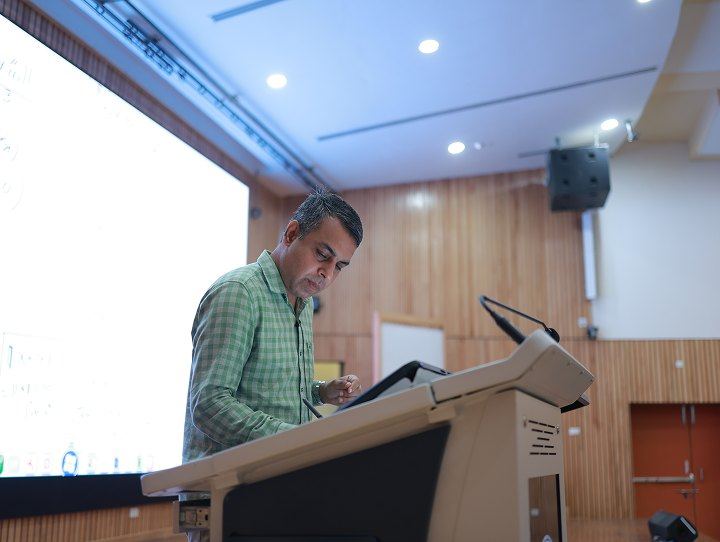 A professor speaking from a lectern in an auditorium