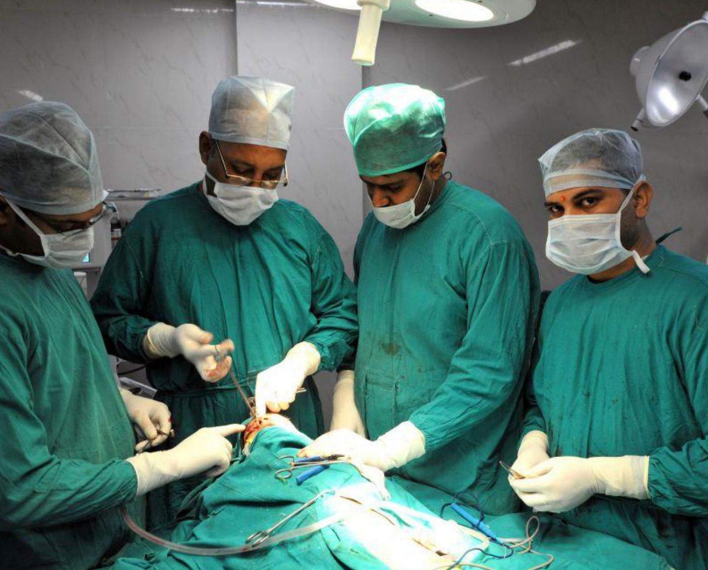 Surgeons in green scrubs performing an operation