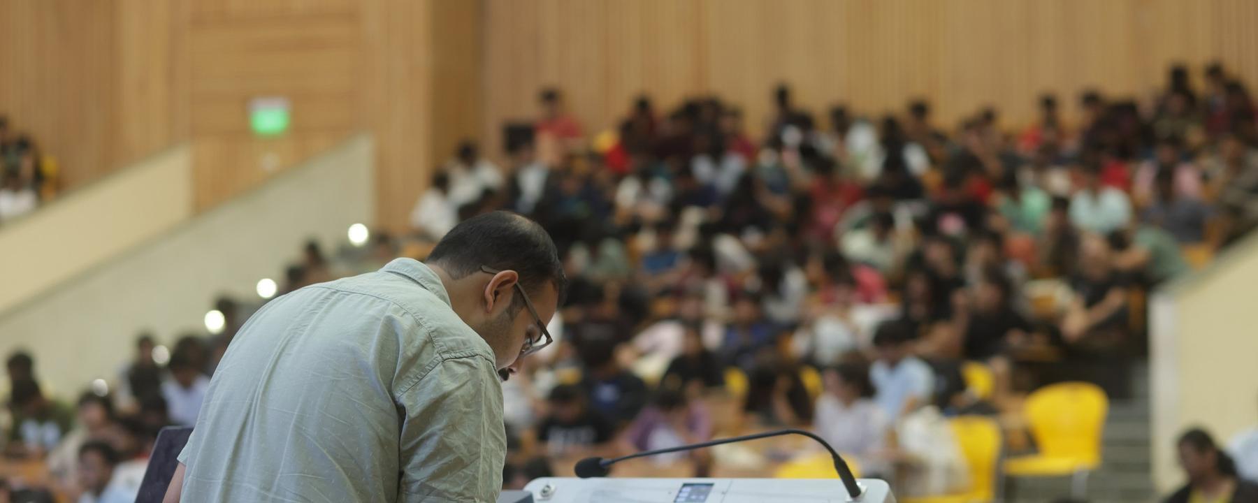 A faculty member lecturing to a full auditorium