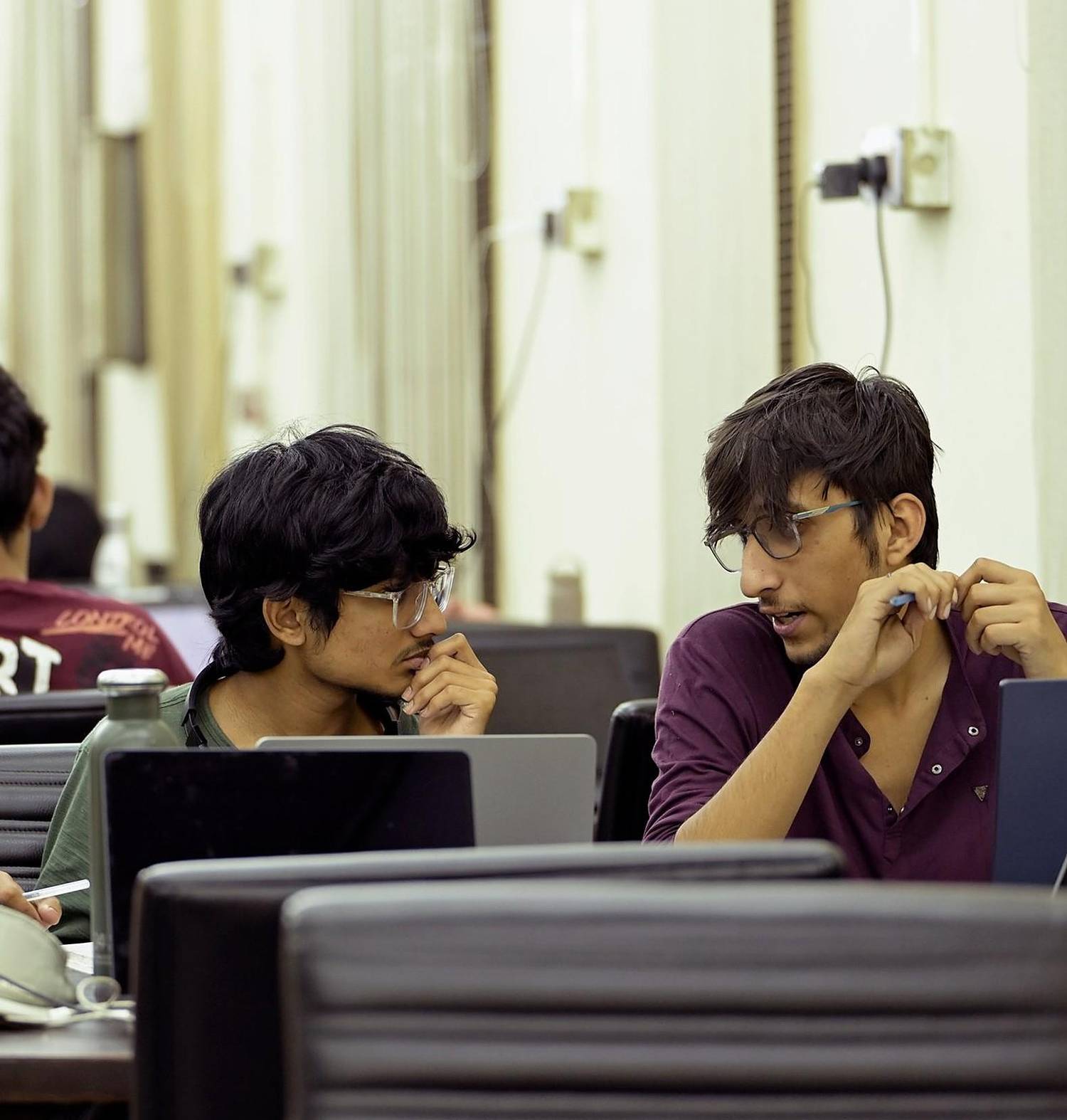 Two students working together on laptops in a computer lab